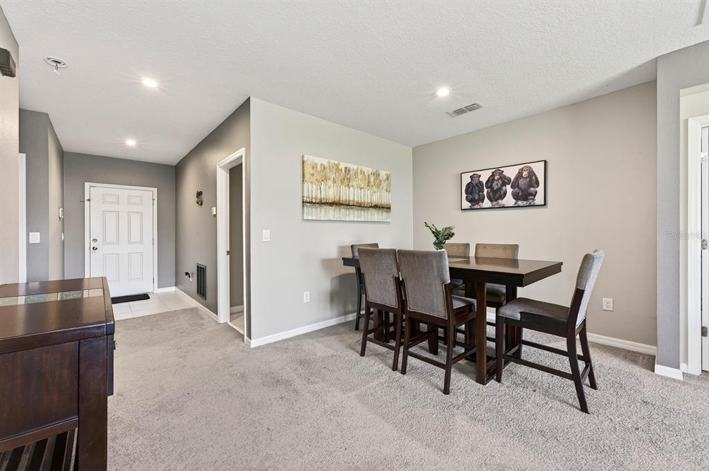 A dining room with a dark wood table, gray upholstered chairs, and two wall art pieces — 596 MEADOW BEND DRIVE, DAVENPORT, FL