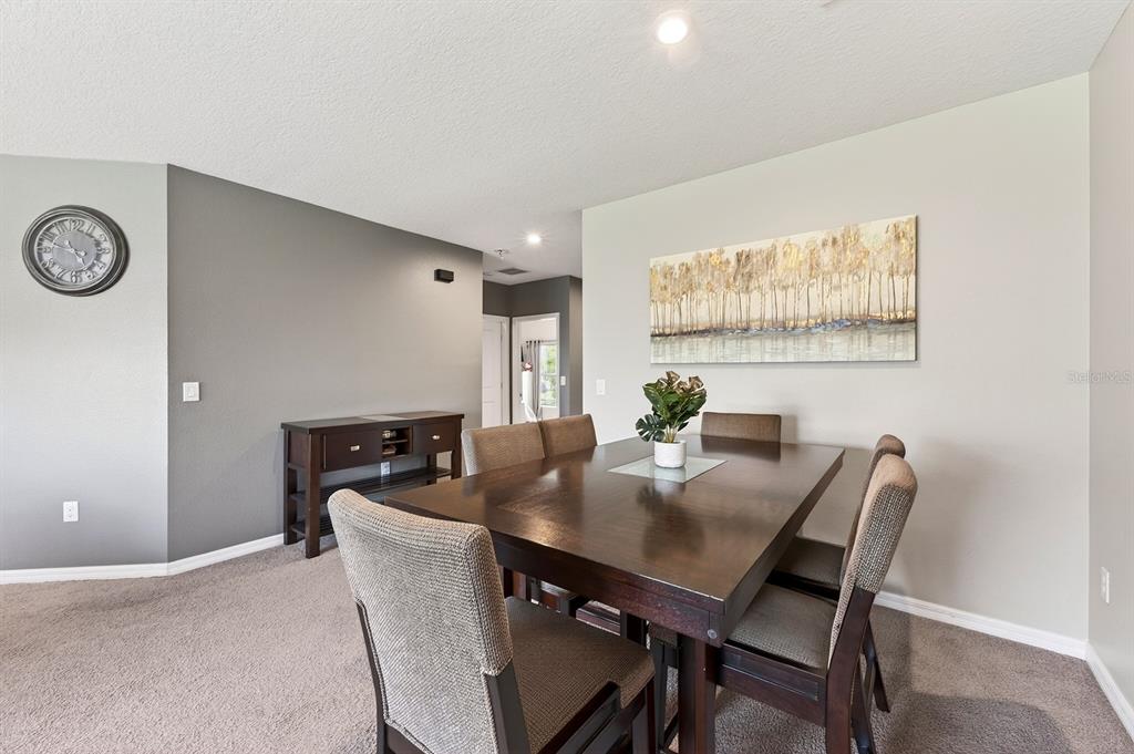A dining room features a dark wood table, upholstered chairs, and a landscape wall painting — 596 MEADOW BEND DRIVE, DAVENPORT, FL