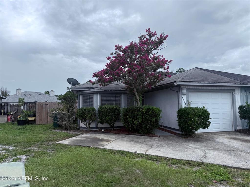 A single-story house exterior features a bay window, a garage, and a blooming crape myrtle — 2288 IRONSTONE DRIVE E, JACKSONVILLE, FL