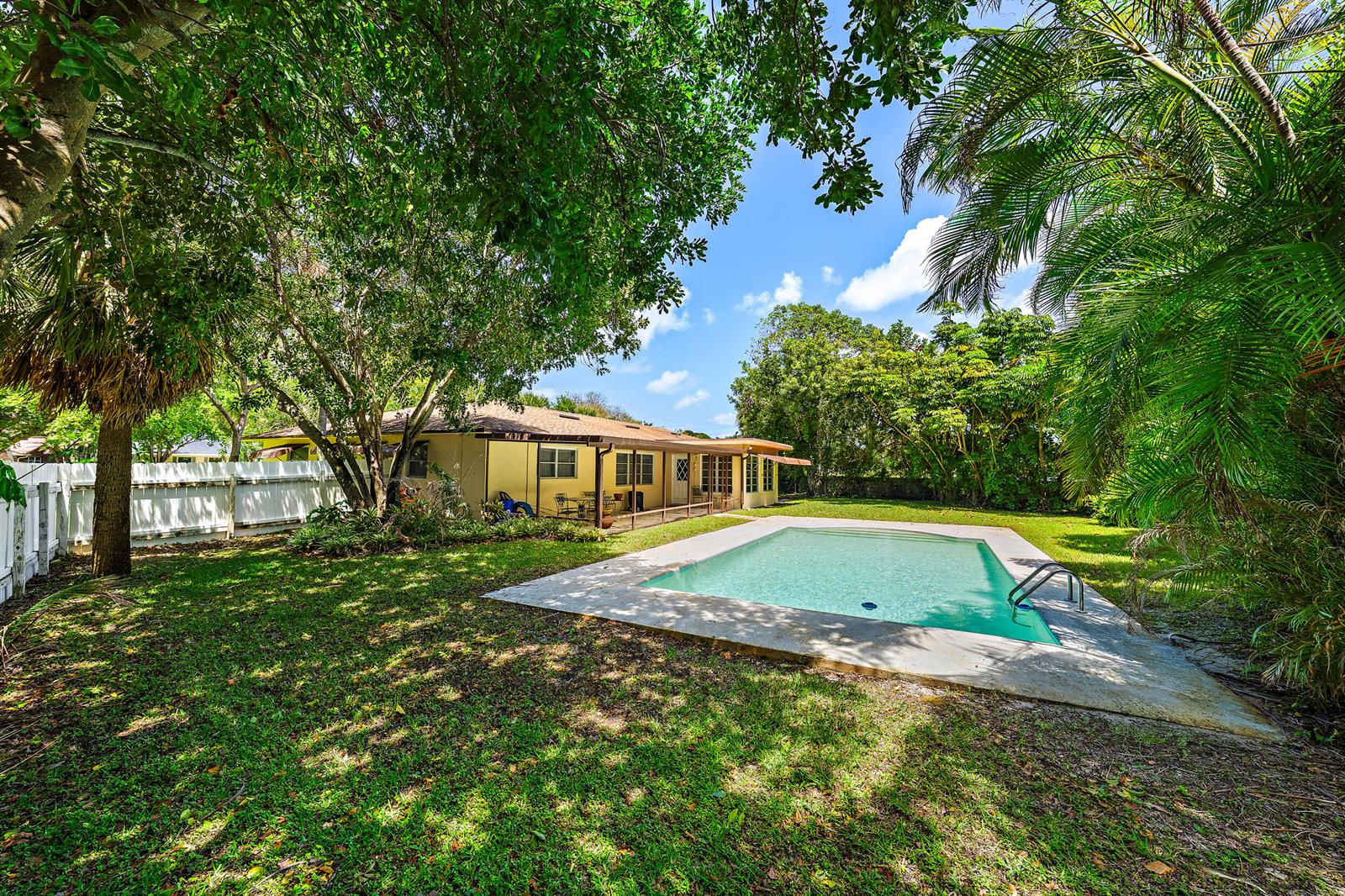 A backyard features a rectangular swimming pool, a covered patio, and mature trees — 844 Anchorage Drive, North Palm Beach FL 33408, NORTH PALM BEACH, FL