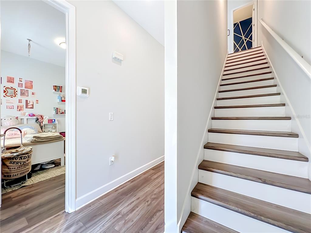 An entryway features wood-look flooring, a staircase, and a small shoe storage bench — 3427 NORMAN LEWIS ALLEY, ORLANDO, FL
