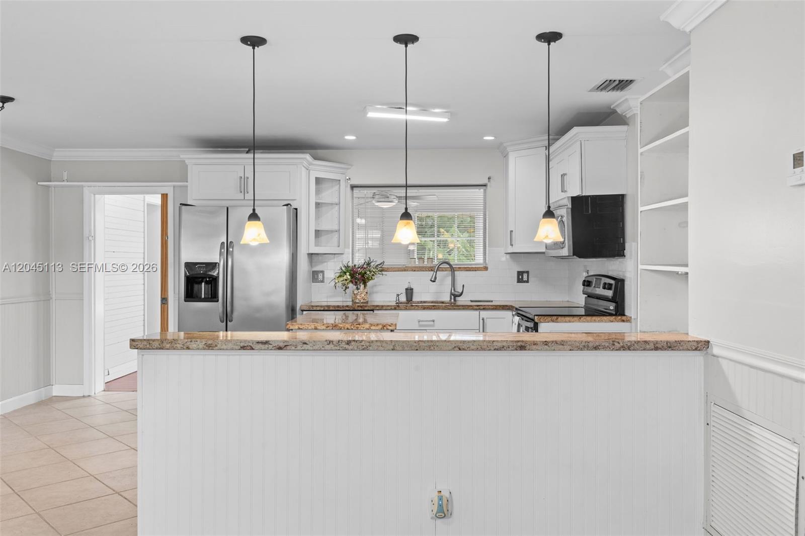A kitchen features white cabinets, granite countertops, stainless steel appliances, and three hanging pendant lights — 795 NW 73rd Ave, Margate FL 33063, MARGATE, FL