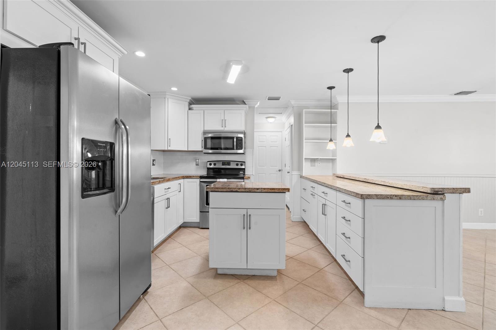 A kitchen features white cabinets, granite countertops, a center island, and stainless steel appliances — 795 NW 73rd Ave, Margate FL 33063, MARGATE, FL