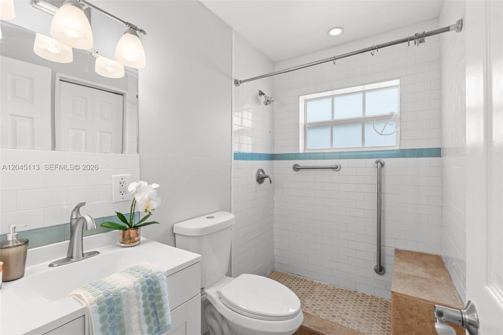 A bathroom features a white vanity, a toilet, and a walk-in shower with white tiles — 795 NW 73rd Ave, Margate FL 33063, MARGATE, FL
