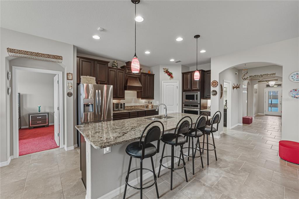 A kitchen with dark wood cabinets, granite countertops, a center island, and four bar stools — 4169 PRIMA LAGO CIRCLE, LAKELAND, FL