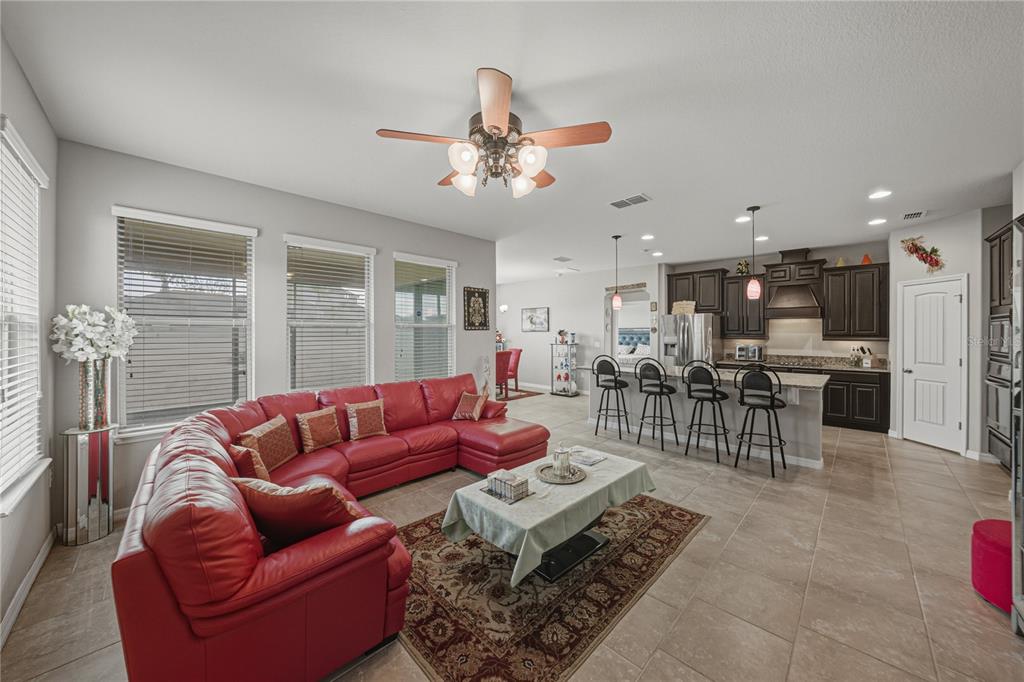 An open-concept living room features a red sectional sofa, tile flooring, and a kitchen island — 4169 PRIMA LAGO CIRCLE, LAKELAND, FL