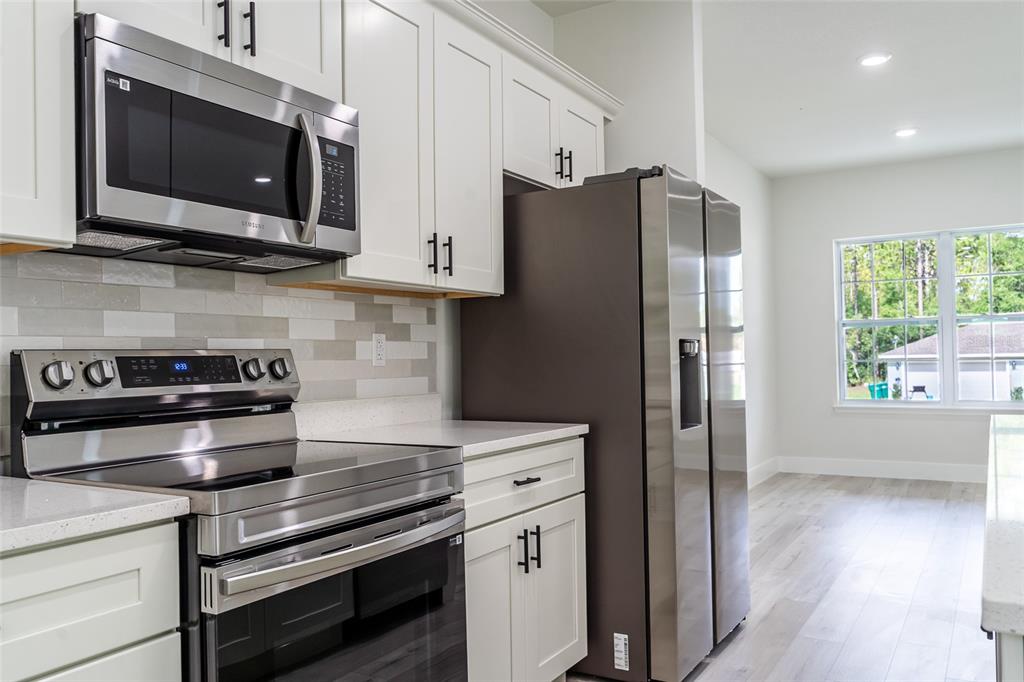 A kitchen features white cabinets, stainless steel appliances, and light-colored countertops — 10955 N DRAGONIS DRIVE, CITRUS SPRINGS, FL