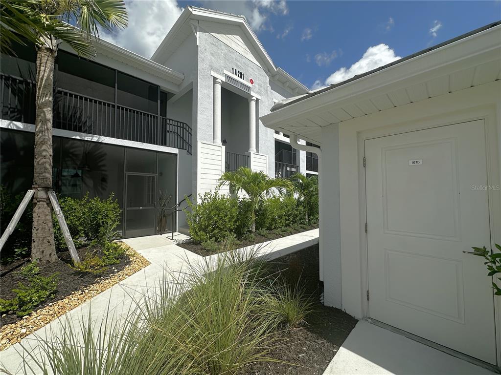 Exterior view of a multi-story building with a white door labeled 1615 in front — 14261 HERITAGE LANDING BOULEVARD UNIT 1615, PUNTA GORDA, FL