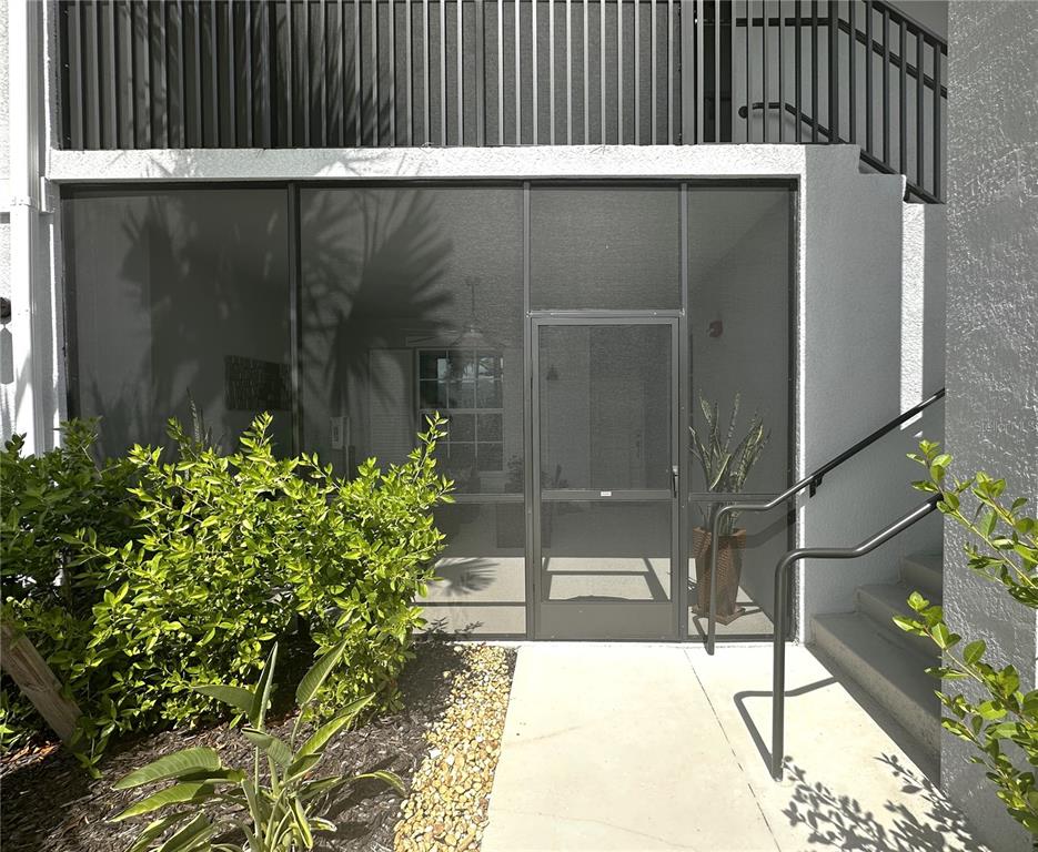 A ground-level patio with a screen door and enclosure sits beside a concrete staircase — 14261 HERITAGE LANDING BOULEVARD UNIT 1615, PUNTA GORDA, FL
