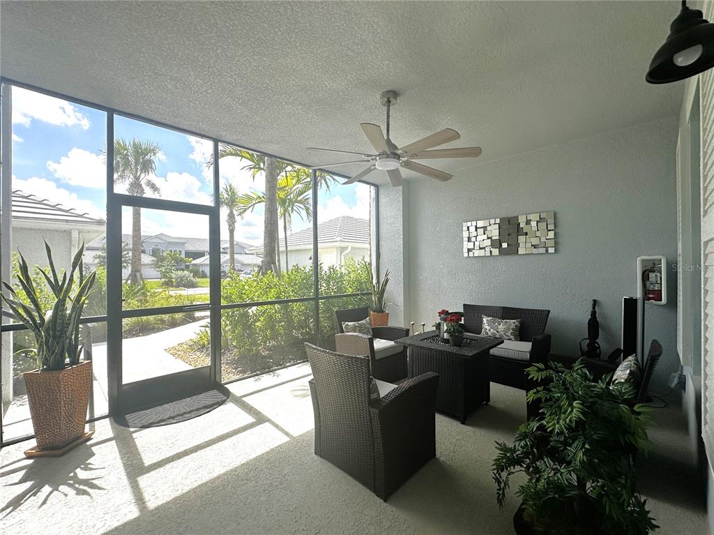 A screened-in patio features wicker furniture, a ceiling fan, and views of a landscaped neighborhood — 14261 HERITAGE LANDING BOULEVARD UNIT 1615, PUNTA GORDA, FL