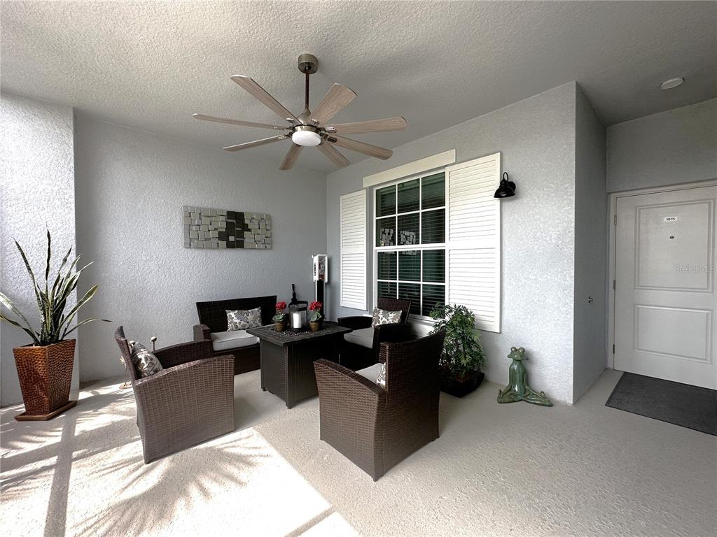 A covered patio features wicker furniture, a ceiling fan, and a white door — 14261 HERITAGE LANDING BOULEVARD UNIT 1615, PUNTA GORDA, FL
