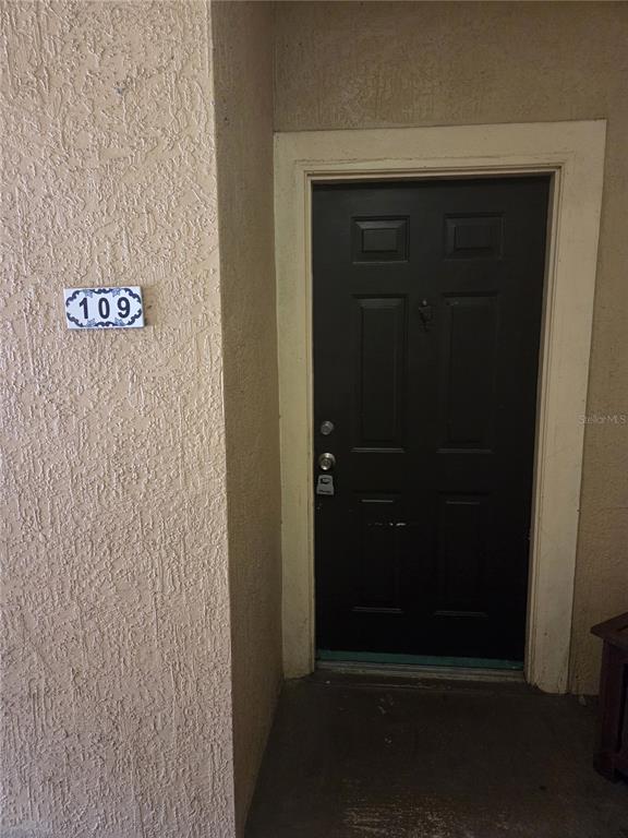 A dark-colored front door with a number 109 sign on a textured beige wall — 5536 METROWEST BOULEVARD UNIT 8-109, ORLANDO, FL