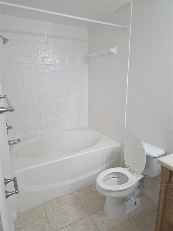 A bathroom features a white oval soaking tub with tiled walls and a white toilet — 5536 METROWEST BOULEVARD UNIT 8-109, ORLANDO, FL