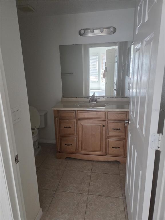 A bathroom features a wooden vanity with a sink, a mirror, and a toilet — 5536 METROWEST BOULEVARD UNIT 8-109, ORLANDO, FL