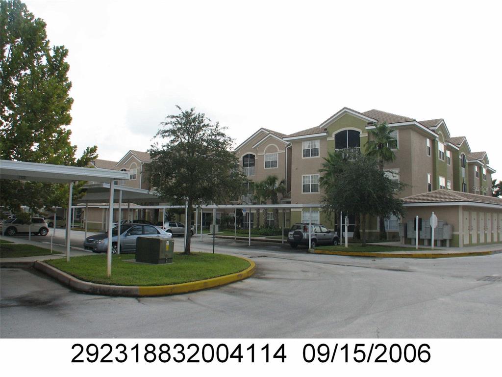 A multi-story apartment building with covered parking spaces and a paved driveway — 4833 CYPRESS WOODS DRIVE UNIT 4114, ORLANDO, FL