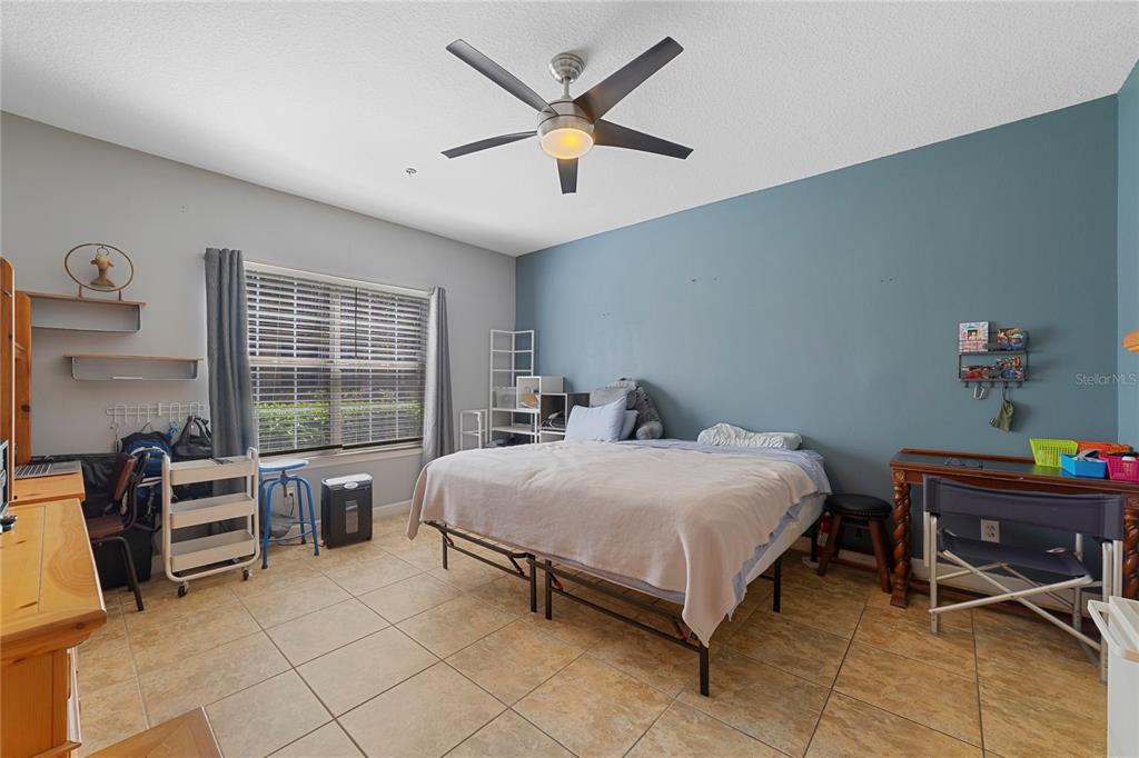 A bedroom features a bed, a ceiling fan, tile flooring, and a blue accent wall — 4833 CYPRESS WOODS DRIVE UNIT 4114, ORLANDO, FL