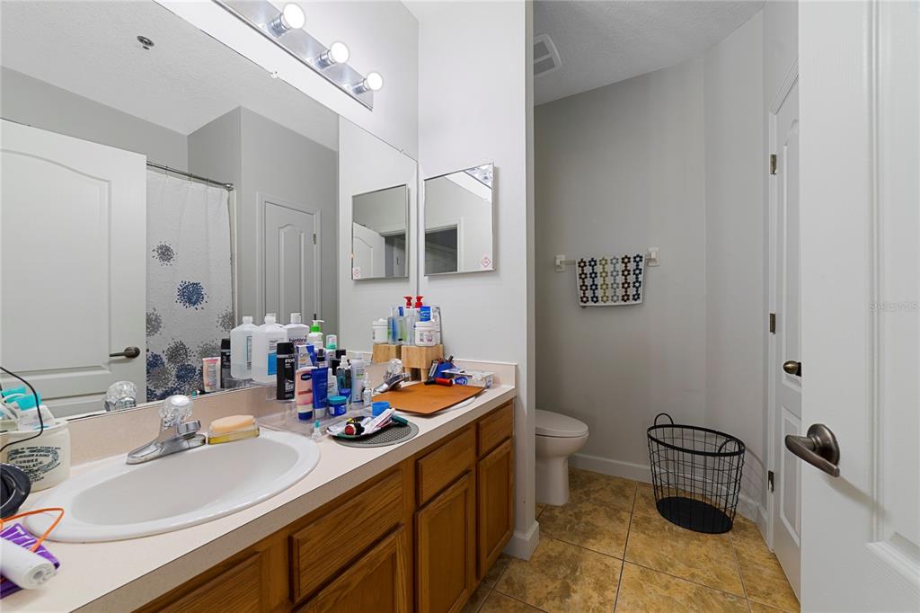 A bathroom features a wooden vanity, a large mirror, and a separate toilet area — 4833 CYPRESS WOODS DRIVE UNIT 4114, ORLANDO, FL