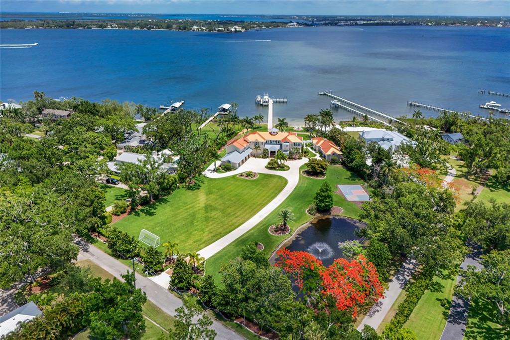 An aerial view shows a large waterfront estate with a private dock and pond — 1707 71ST STREET NW, BRADENTON, FL