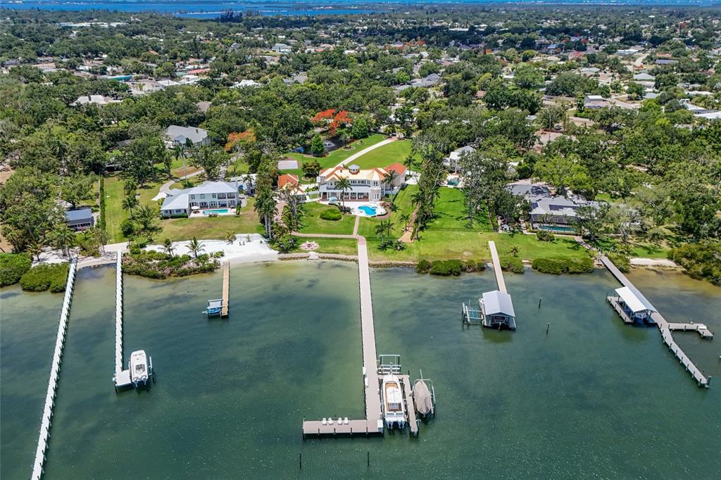 An aerial view shows a waterfront estate with multiple docks, a swimming pool, and lush landscaping — 1707 71ST STREET NW, BRADENTON, FL