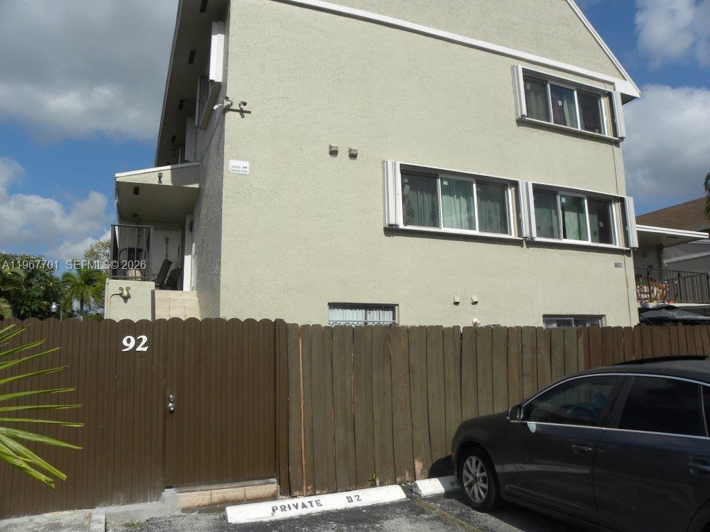 A three-story building with a wooden fence and a parked car in the foreground — 15690 SW 82nd Cir Ln # 1, Miami FL 33193, MIAMI, FL