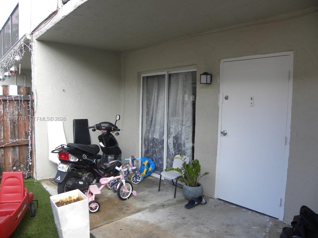 A concrete patio features a scooter, a child's tricycle, a potted plant, and a door — 15690 SW 82nd Cir Ln # 1, Miami FL 33193, MIAMI, FL