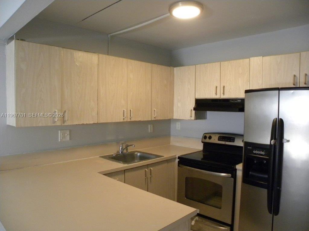 A kitchen features light wood cabinets, stainless steel appliances, and a beige countertop — 15690 SW 82nd Cir Ln # 1, Miami FL 33193, MIAMI, FL
