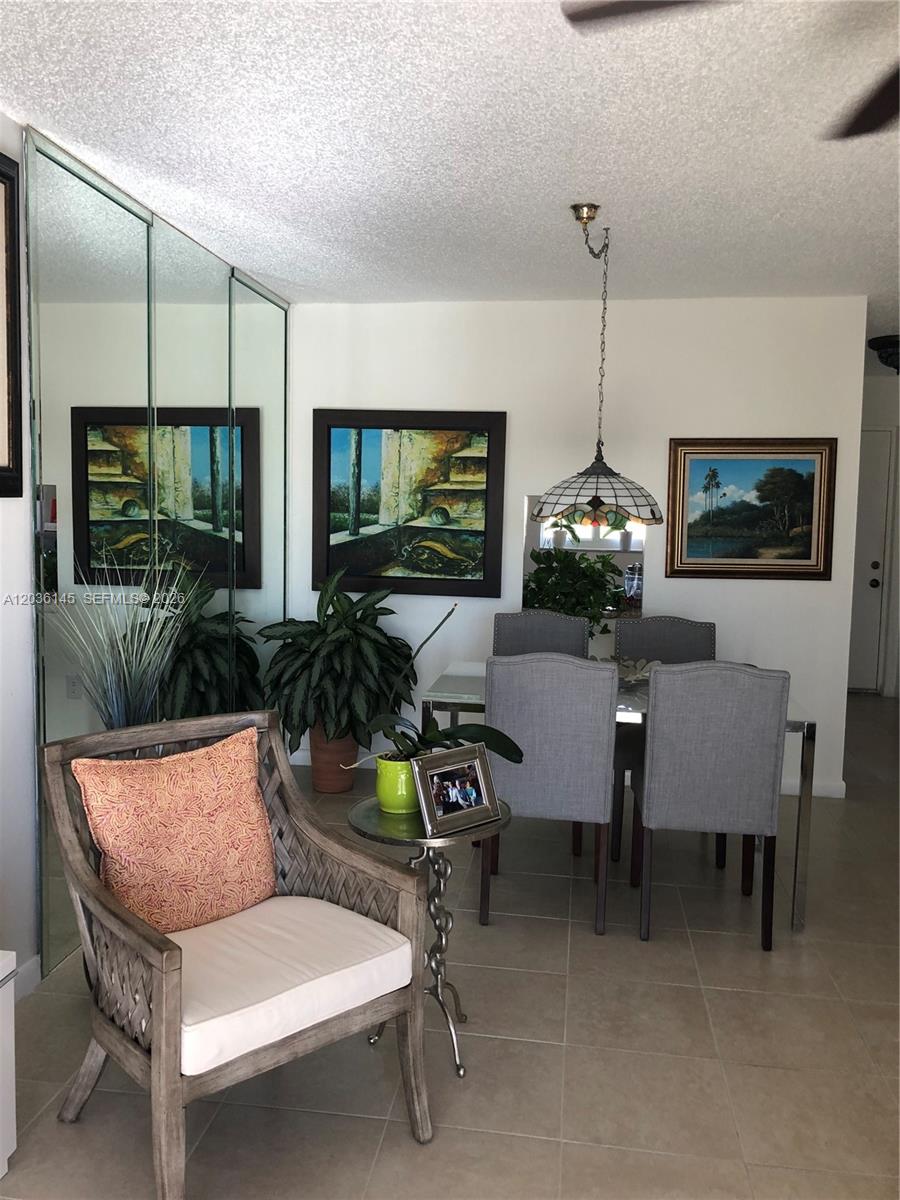 A dining area features a glass table, gray upholstered chairs, a pendant light, and mirrors — 7722 Camino Real # 415, Miami FL 33143, MIAMI, FL