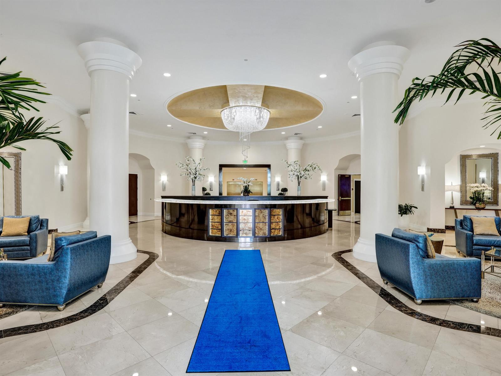 A grand hotel lobby features a curved reception desk, large white columns, and blue seating — 3720 S Ocean Boulevard, Highland Beach FL 33487, HIGHLAND BEACH, FL