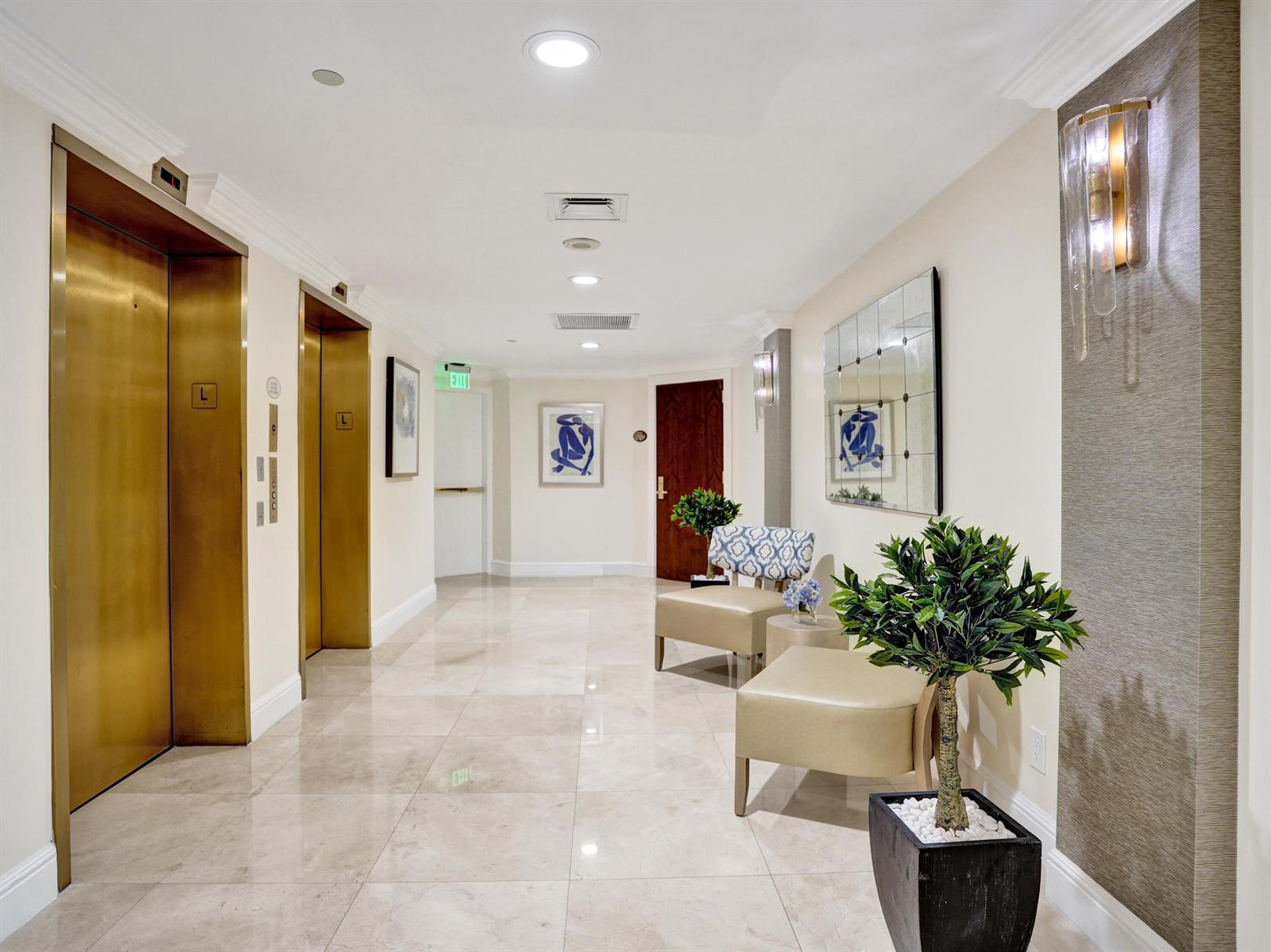 A hallway features two gold elevator doors, beige tile flooring, seating, and decorative wall art — 3720 S Ocean Boulevard, Highland Beach FL 33487, HIGHLAND BEACH, FL