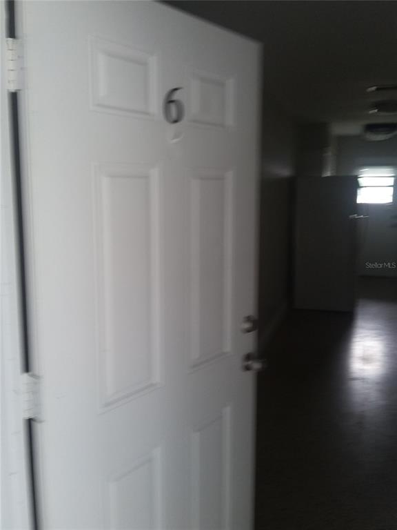 A white door labeled with the number six opens into a dimly lit interior space — 1710 S WASHINGTON AVENUE UNIT 06, TITUSVILLE, FL