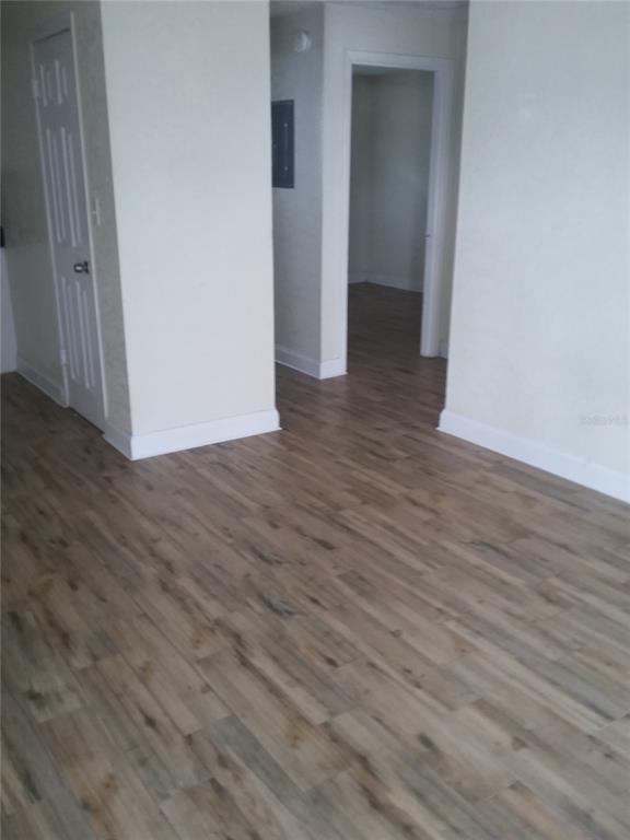 An interior view shows a room with wood-look flooring and a doorway leading to another space — 1710 S WASHINGTON AVENUE UNIT 06, TITUSVILLE, FL