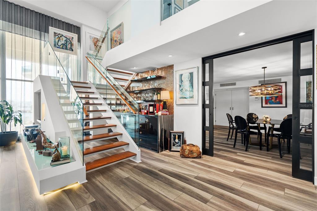 A modern interior features a wooden staircase with glass railings, a wet bar, and dining area — 25 LUIS MUNOZ RIVERA UNIT 408, SAN JUAN, PR