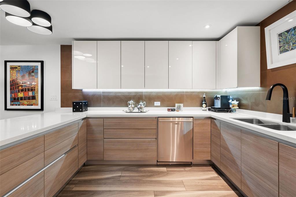 A modern kitchen features white upper cabinets, wood-grain lower cabinets, and white countertops — 25 LUIS MUNOZ RIVERA UNIT 408, SAN JUAN, PR