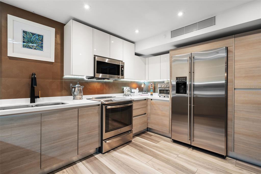 A modern kitchen features wood-grain lower cabinets, white upper cabinets, and stainless steel appliances — 25 LUIS MUNOZ RIVERA UNIT 408, SAN JUAN, PR