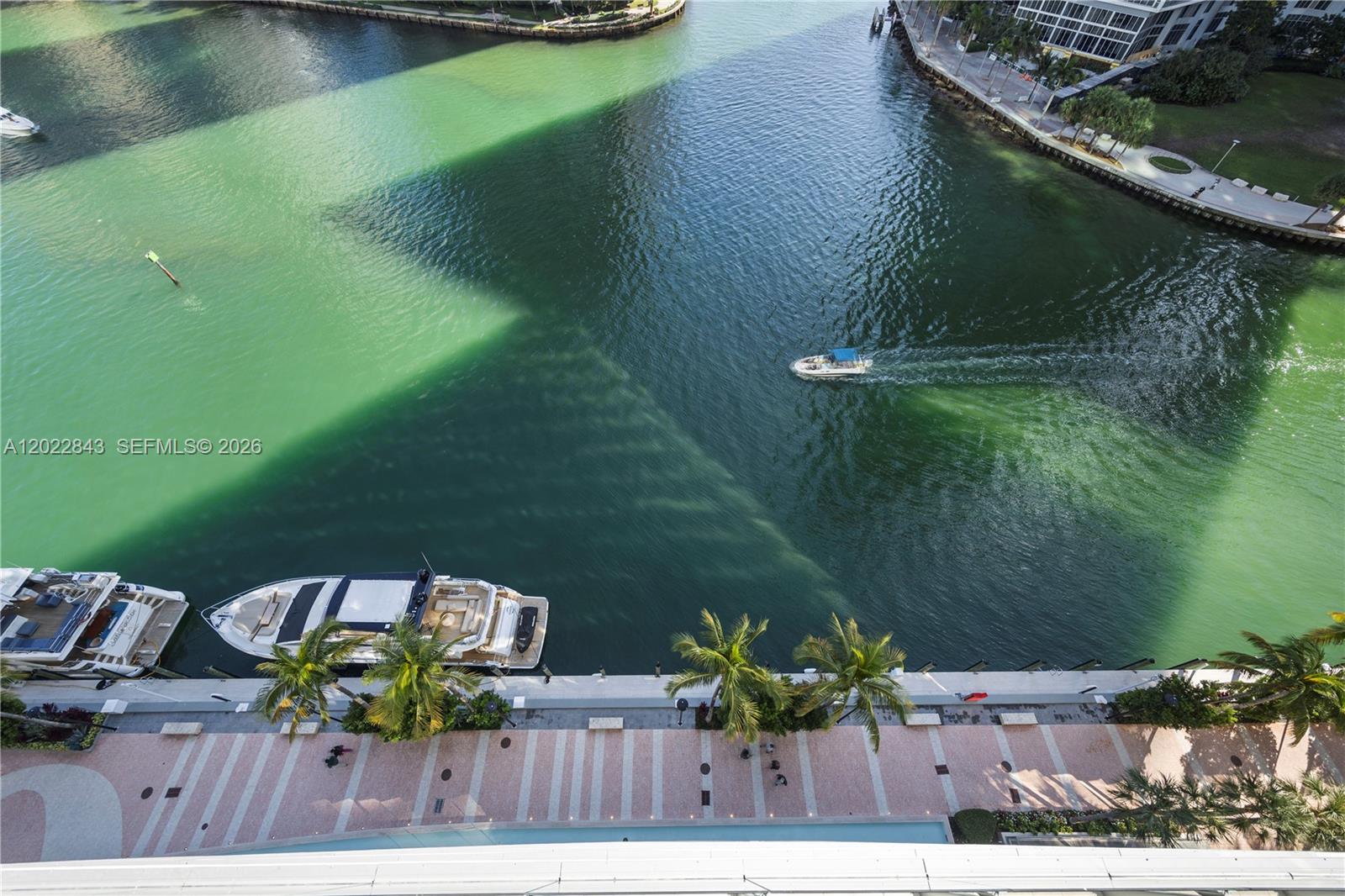 An aerial view shows a boat cruising on a canal next to a paved walkway — 300 Biscayne Blvd Way # 1102, Miami FL 33131, MIAMI, FL