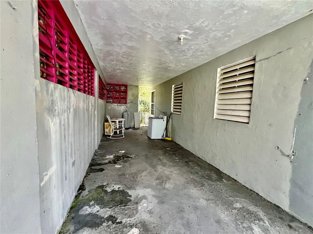 An outdoor covered patio features concrete flooring, pink louvered vents, and a white washing machine — 233 Bo Cienaga Alta MALPICA, RIO GRANDE, PR
