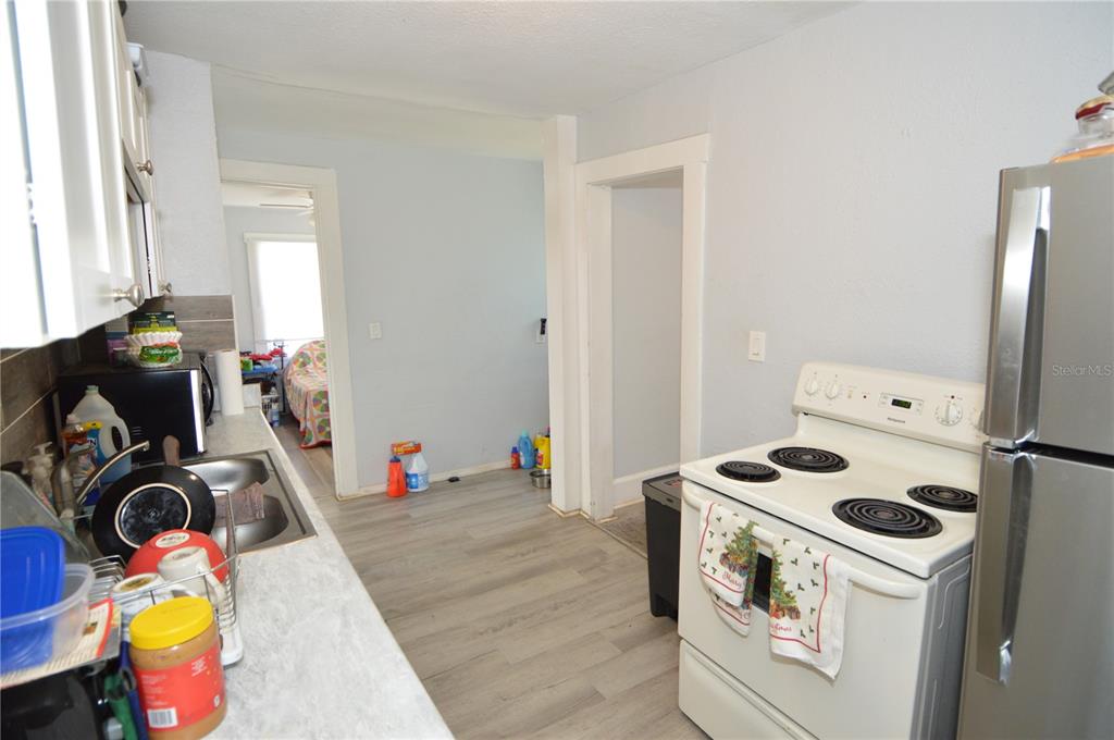 A kitchen with light gray flooring, white cabinets, a white stove, and a stainless refrigerator — 2351 25TH AVENUE S, ST PETERSBURG, FL
