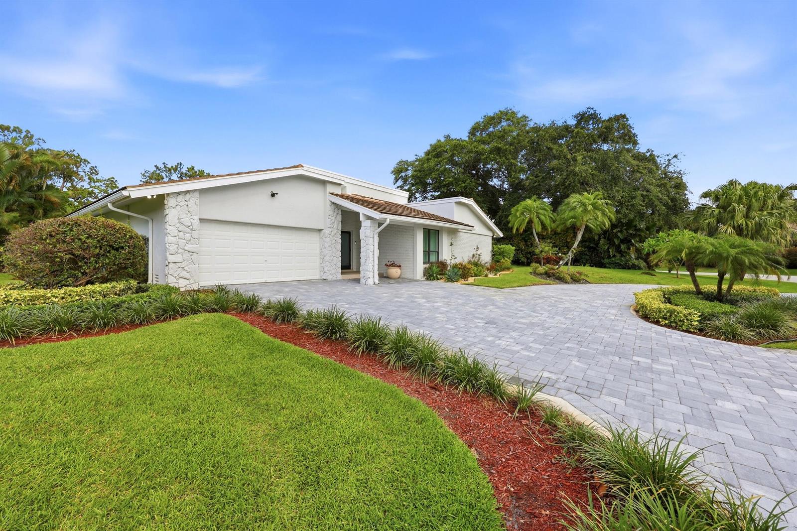 A single-story house with a white stone facade, a paved driveway, and a landscaped lawn — 624 W Lakewoode Circle W, Delray Beach FL 33445, DELRAY BEACH, FL