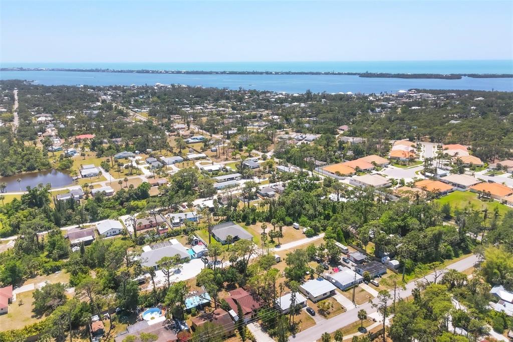 An aerial view shows a residential neighborhood with many trees near a large body of water — 521 ARTISTS AVENUE, ENGLEWOOD, FL