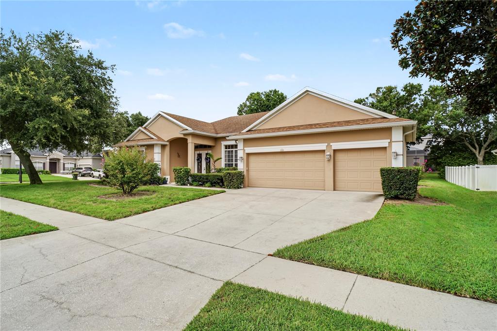 A tan, single-story suburban house features a two-car garage and a concrete driveway — 2648 VALIANT DRIVE, CLERMONT, FL