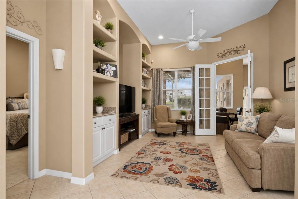 A living room features built-in shelving, a floral area rug, a sofa, and French doors — 2648 VALIANT DRIVE, CLERMONT, FL