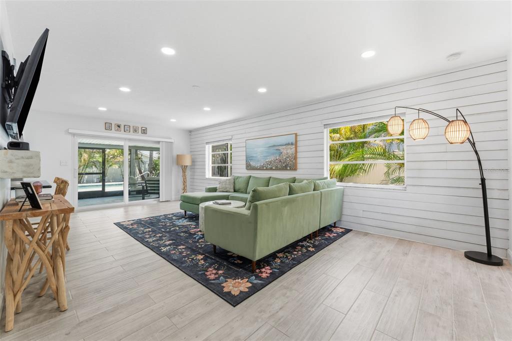 A living room features a green sectional sofa, shiplap walls, and a dark floral rug — 2701 67TH WAY N, ST PETERSBURG, FL
