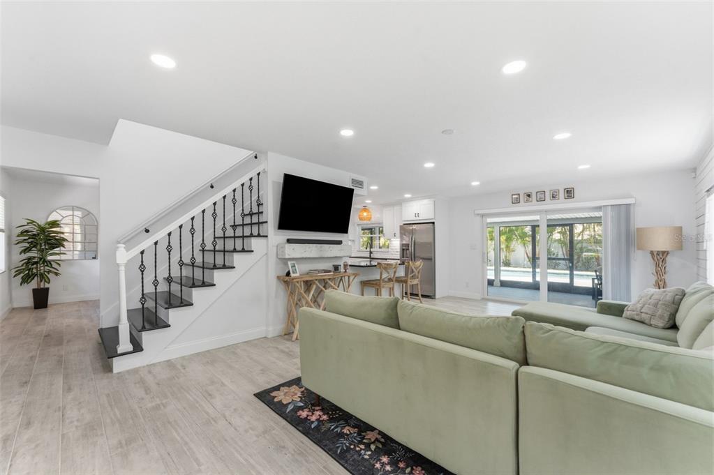 A living room features a staircase, a light green sectional sofa, and a kitchen beyond — 2701 67TH WAY N, ST PETERSBURG, FL