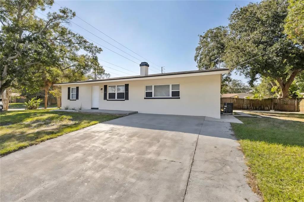 A single-story house with a light-colored exterior, a concrete driveway, and a chimney — 1004 N BETTY LANE, CLEARWATER, FL