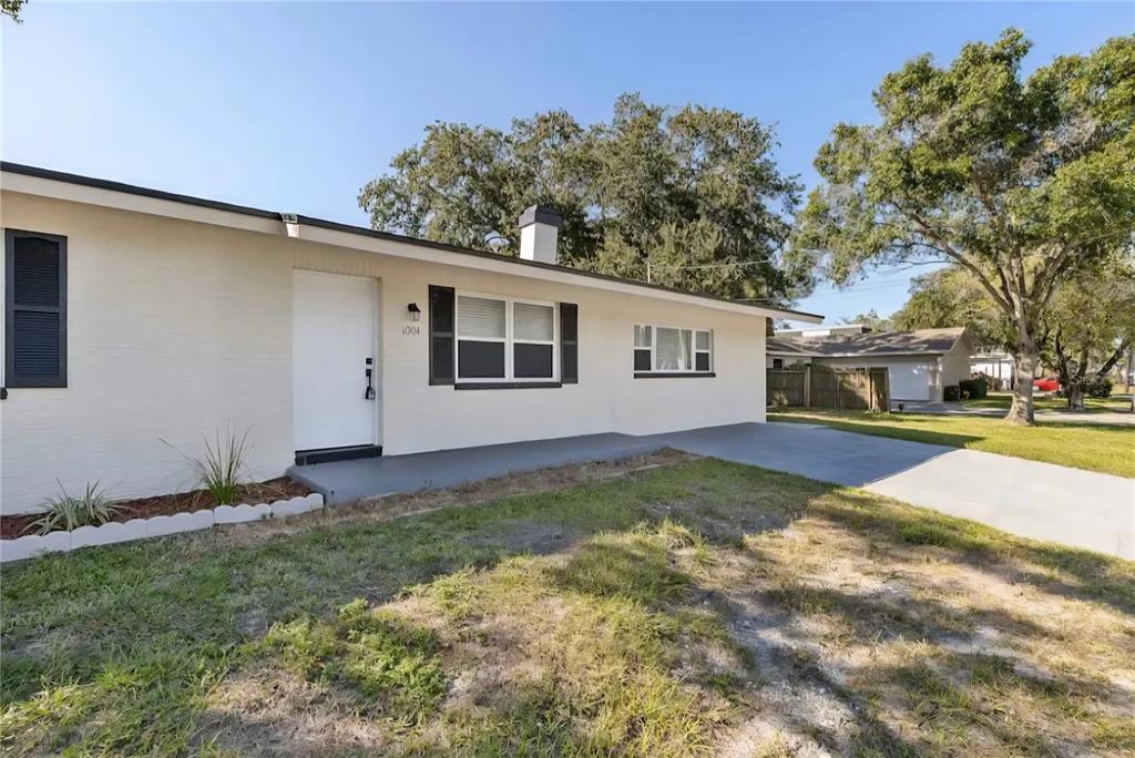 A single-story house with a white brick exterior, dark shutters, and a concrete driveway — 1004 N BETTY LANE, CLEARWATER, FL