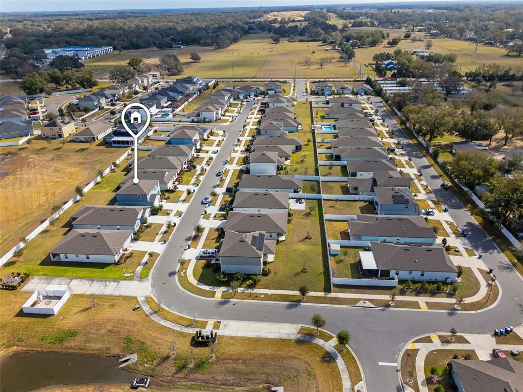 This aerial view shows a suburban neighborhood with multiple single-family homes and a retention pond — 9644 SUMMERS CAY CIRCLE, THONOTOSASSA, FL