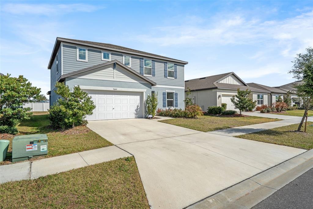 A two-story house with blue siding, a white garage door, and a concrete driveway — 9644 SUMMERS CAY CIRCLE, THONOTOSASSA, FL