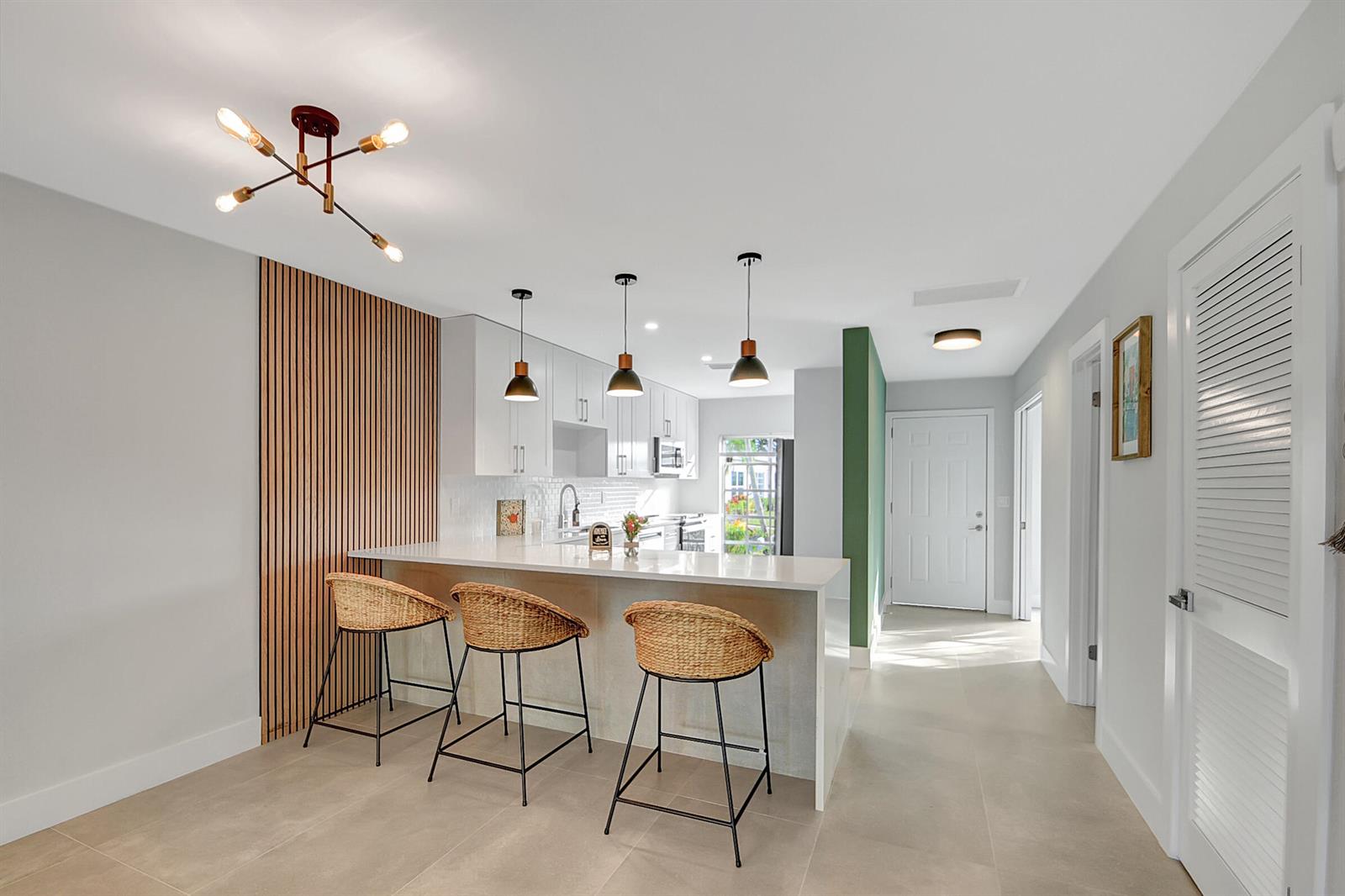 A modern kitchen features white cabinetry, stainless steel appliances, a subway tile backsplash, and wood-slat wall — 13602 Via Flora Apt C, Delray Beach FL 33484, DELRAY BEACH, FL