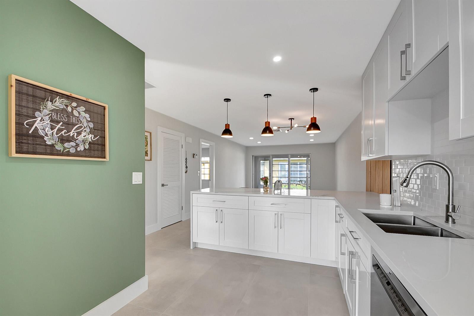 A spacious lounge features a high tray ceiling, wood-slat accent wall, and multiple seating areas — 13602 Via Flora Apt C, Delray Beach FL 33484, DELRAY BEACH, FL