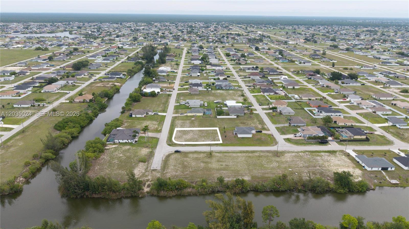 An aerial view shows a vacant residential lot outlined in white within a suburban neighborhood — 2009 NW 2ND AVE, Cape Coral FL 33993, CAPE CORAL, FL